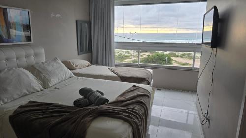 a living room with a couch and a large window at Apartamento Duplex na Praia Grande 108 VISTA MAR in Arraial do Cabo
