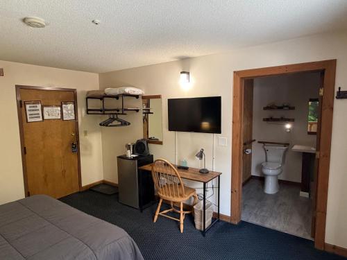 a hotel room with a bed and a desk and a toilet at Mountain Sports Inn in Killington