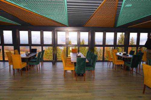 a dining room with tables and chairs and windows at Planinska Kraljica in Gornje Pale