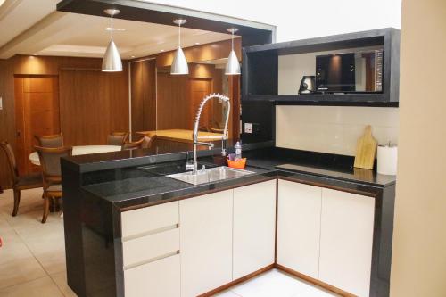 a kitchen with white cabinets and a sink at GramadoPenthouse 4quartos 3banheiros in Gramado