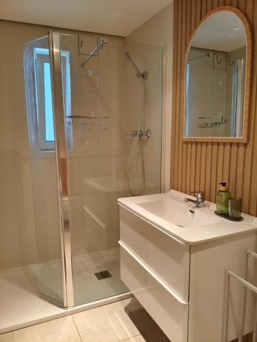 a white bathroom with a shower and a sink at Golden Refúgio das Andorinhas in Cabanas de Tavira