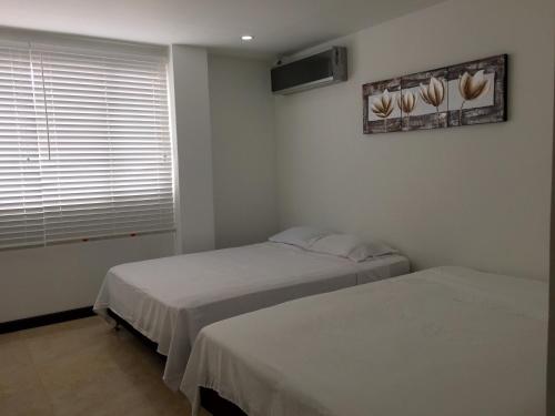 two beds in a small room with a window at Apartamentos Martinez in San Andrés