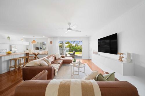 a living room with two brown couches and a kitchen at Palm Cove Retreat - Walk to beach & CBD in Maroochydore
