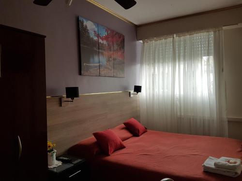 a bedroom with a red bed and a window at San Carlos Hotel in Buenos Aires