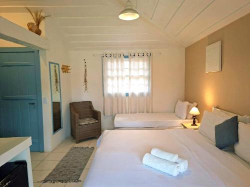 a bedroom with two beds and a chair in it at Pousada dos Pássaros Geribá in Búzios