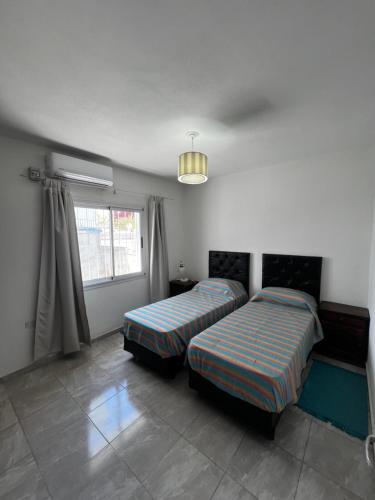 ein Schlafzimmer mit zwei Betten und einem Fenster in der Unterkunft Departamento con patio y garaje y parrilla in San Fernando del Valle de Catamarca