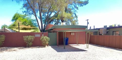 a fence in front of a house with a building at Cute Bungalow 1 Mile from U of A in Tucson