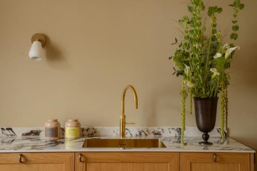 Four Suites Copenhagen في كوبنهاغن: طاولة مطبخ مع حوض و مزهرية مع الزهور