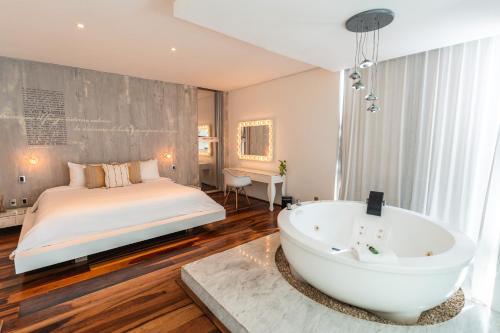 a bedroom with a bed and a bath tub at Be Playa Hotel Boutique & Rooftop Bar - Adults Only in Playa del Carmen