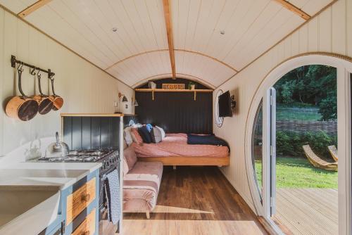 a kitchen with a bed in a tiny house at The Shepherd's Hut at Hidden Wood Glamping in Corsley