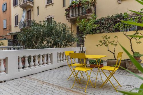 ミラノにあるホテル デル ソルの黄色のテーブルと椅子が並ぶパティオ