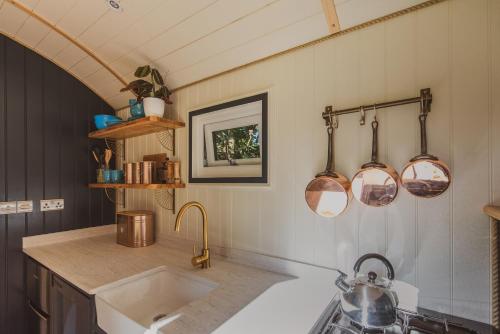 a kitchen with a sink and some pots and pans at The Shepherd's Hut at Hidden Wood Glamping in Corsley