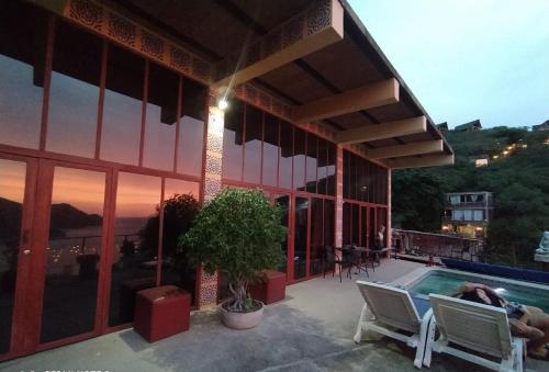 een gebouw met een zwembad en een persoon die op een stoel ligt bij Artists loft w panoramic views pool in Taganga