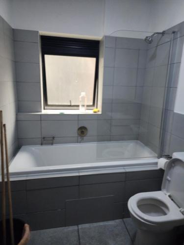 a bathroom with a tub and a toilet and a window at The white house in Midrand