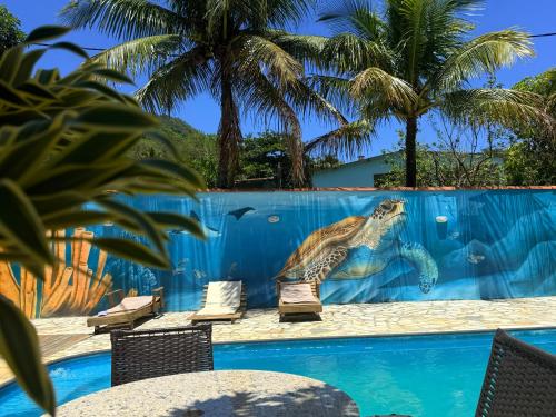 a turtle mural on a fence next to a swimming pool at Pousada Recanto dos Lima in Praia do Bananal