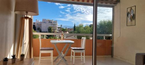 Un balcón con mesa y sillas y una gran ventana. en Appartement Port Santa Lucia, en Saint-Raphaël