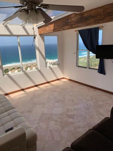 a living room with a ceiling fan and views of the ocean at Oceanfront Hideaway mainfloor in Isabela