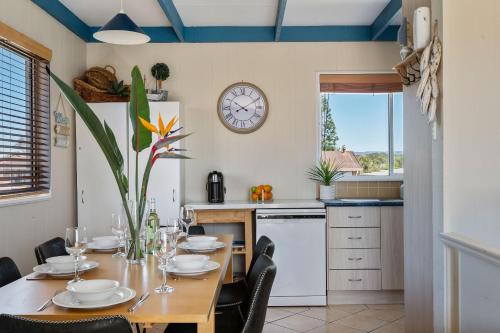 a kitchen with a table with chairs and a clock on the wall at Oceans 13 in Manyana