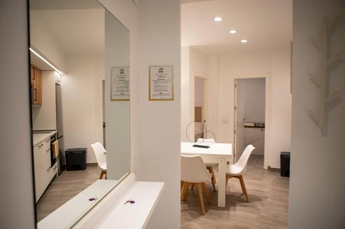 Una cocina y un comedor con una mesa y sillas blancas. en Apartamentos Palma del Río CAROLA, en Linares