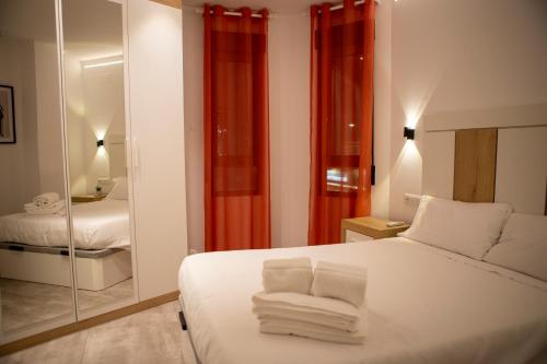 Un dormitorio con una cama blanca y un espejo. en Apartamentos Palma del Río CAROLA, en Linares