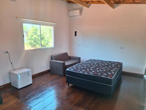 a bedroom with a bed and a chair and a window at Casa Boraceia Litoral Norte SP in São Sebastião