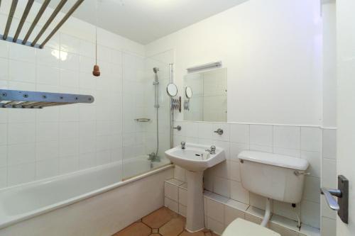 a white bathroom with a sink and a toilet at Neat 2 bedroom ground floor flat in Beckenham