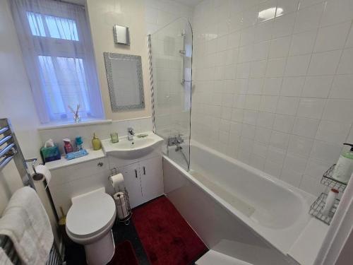 a white bathroom with a toilet and a sink at Hornchurch Cozy 2-Bed Flat with Street Parking in Hornchurch