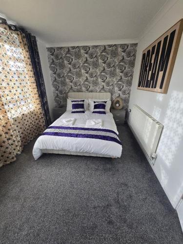 a bedroom with a large bed with blue pillows at Hornchurch Cozy 2-Bed Flat with Street Parking in Hornchurch