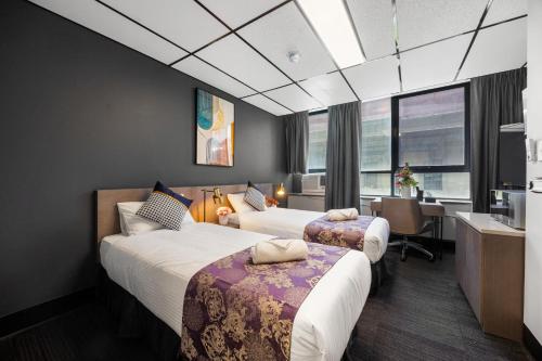 a hotel room with two beds and a desk at Eminence on Bank in Adelaide