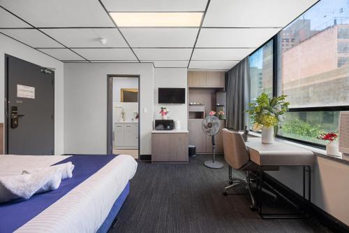 a bedroom with a bed and a desk and a window at Eminence on Bank in Adelaide
