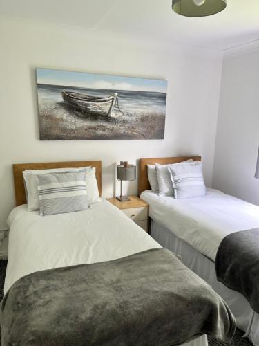 a bedroom with two beds and a painting of a boat at River house in Birnam