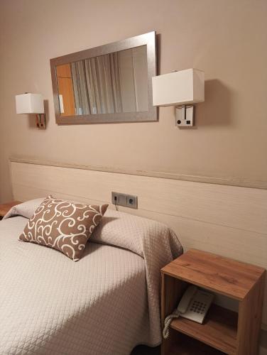 a bedroom with a bed and a mirror on the wall at Hostal Atienzar in Albacete