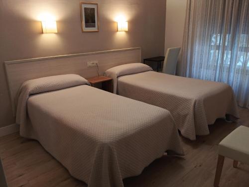 a hotel room with three beds with white sheets at Hostal Atienzar in Albacete