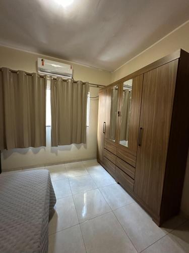 a bedroom with a bed and a wooden cabinet at Casa da paz in Palmas