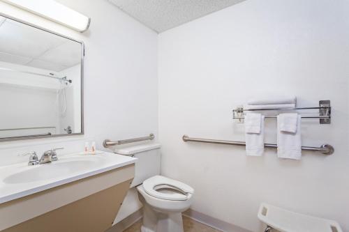 a bathroom with a sink and a toilet and a mirror at Super 8 by Wyndham Oneonta/Cooperstown in Oneonta