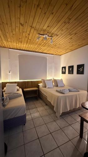 a room with two beds and a wooden ceiling at Pousada Sol e Mar in Farol de Santa Marta