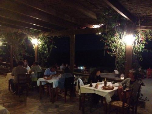 a group of people sitting at tables in a restaurant at night at Gavdos Princess in Gavdos