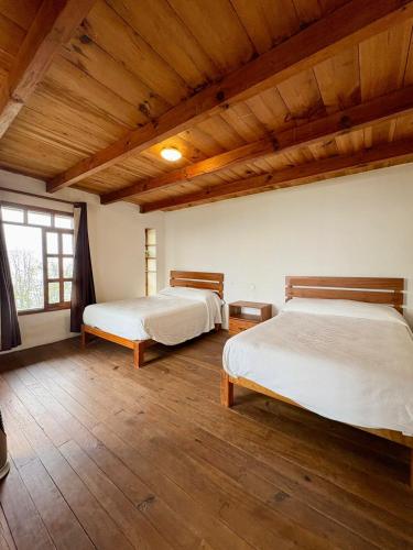 two beds in a room with wooden ceilings at Cabañas Las Camelias in Cuetzalán del Progreso
