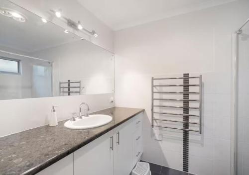 a white bathroom with a sink and a mirror at The Summer Residence Middleton in Middleton
