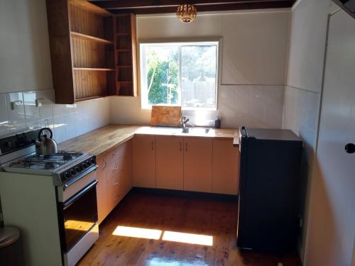 a kitchen with a sink and a stove and a window at Iluka Rainforest Beach Shack Eco-Home in Woombah