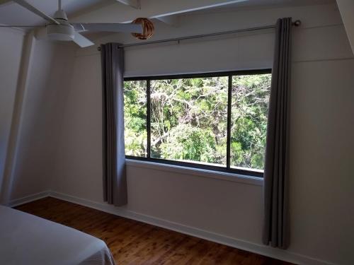 a bedroom with a window with a view of trees at Iluka Rainforest Beach Shack Eco-Home in Woombah