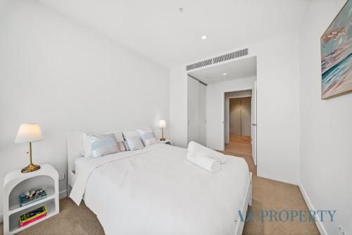 a white bedroom with a white bed and a lamp at Luxury Perth Apartment - City Views RAC Arena Pool & Gym in Perth