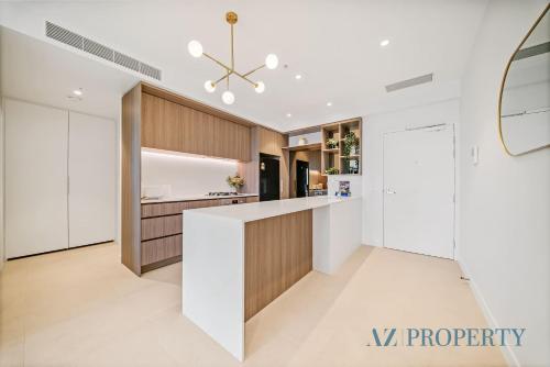 a kitchen with white and wood cabinets and a large island at Luxury Perth Apartment - City Views RAC Arena Pool & Gym in Perth