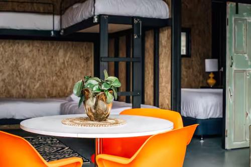 a table with orange chairs and a vase with a plant at Humbug Bunk House & Hot Tub! in St Helens