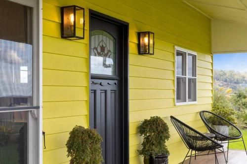 a yellow house with a black door and chairs at The Quince Cottage - 2 Bedrooms in Ravensbourne