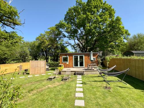 ein winziges Haus mit Hängematte im Hof in der Unterkunft The Hideaway at Hidden Wood Glamping in Corsley