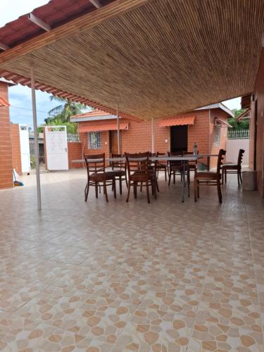 Campement Le Canoë في Oussouye: فناء به طاولات وكراسي خشبية ومبنى