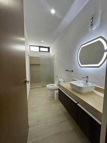 a bathroom with a sink and a toilet and a mirror at Private Canarian house with pool in Conkal
