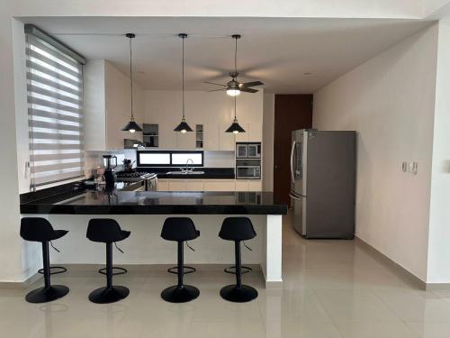a kitchen with a island with bar stools and a refrigerator at Private Canarian house with pool in Conkal