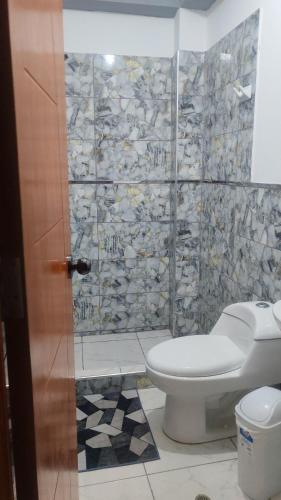 um banheiro com vaso sanitário e uma parede de pedra em Hospedaje Luciana em Pucallpa